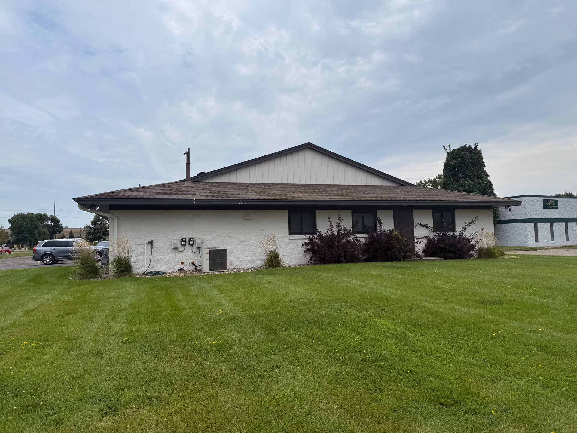 Single-story beige building with dark trim, sloped roof, and well-kept front lawn.