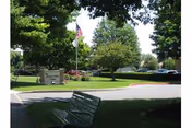 Exterior view of Lebanon Valley Home with a manicured lawn, trees, flag, sign, and bench.