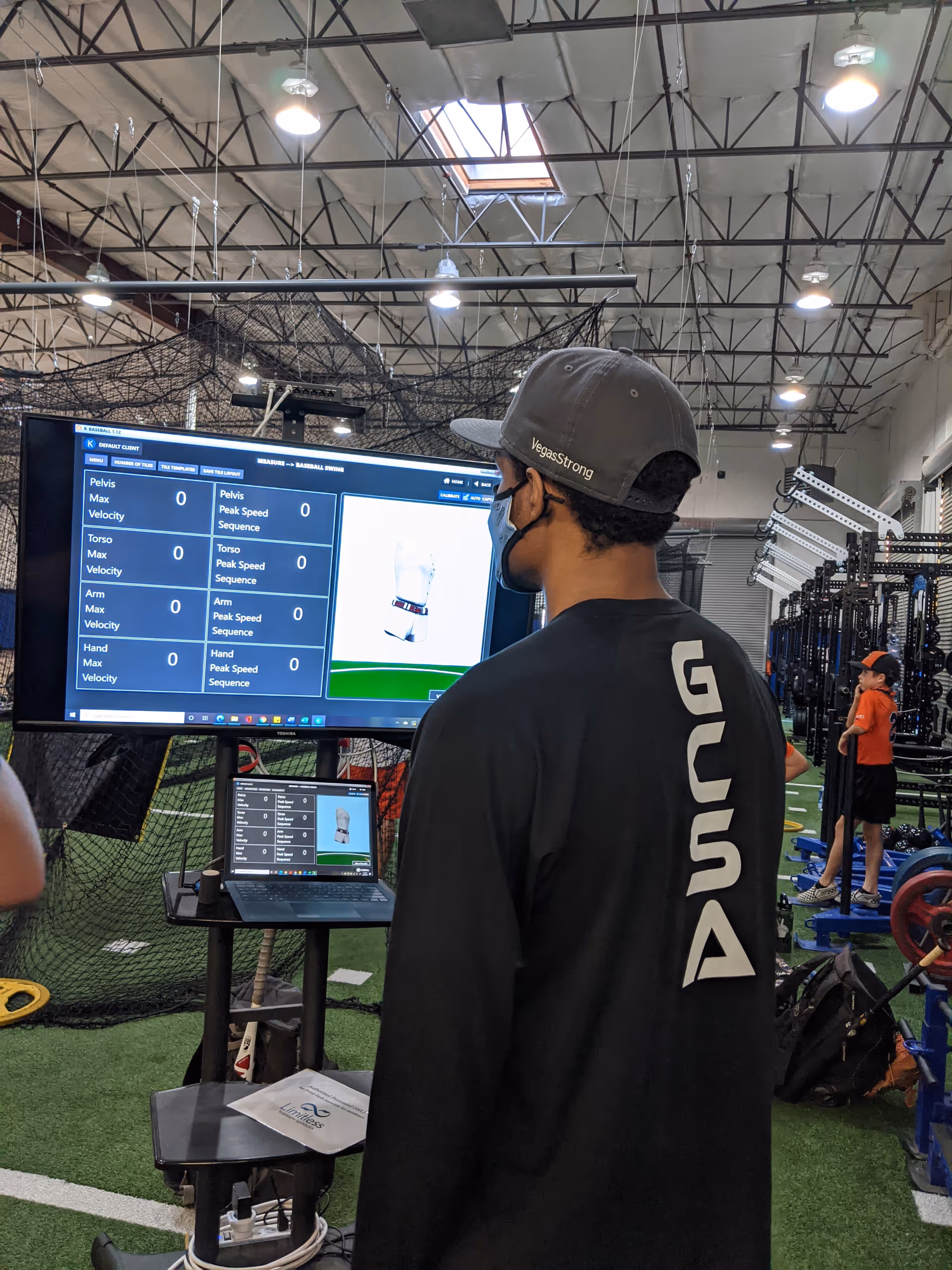 A person watches a large monitor displaying performance data in a rehab gym.