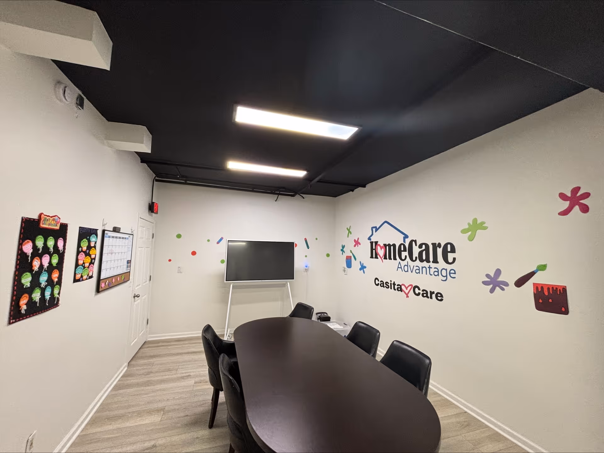 A long conference table with chairs in a bright room featuring Home Care Advantage wall art.