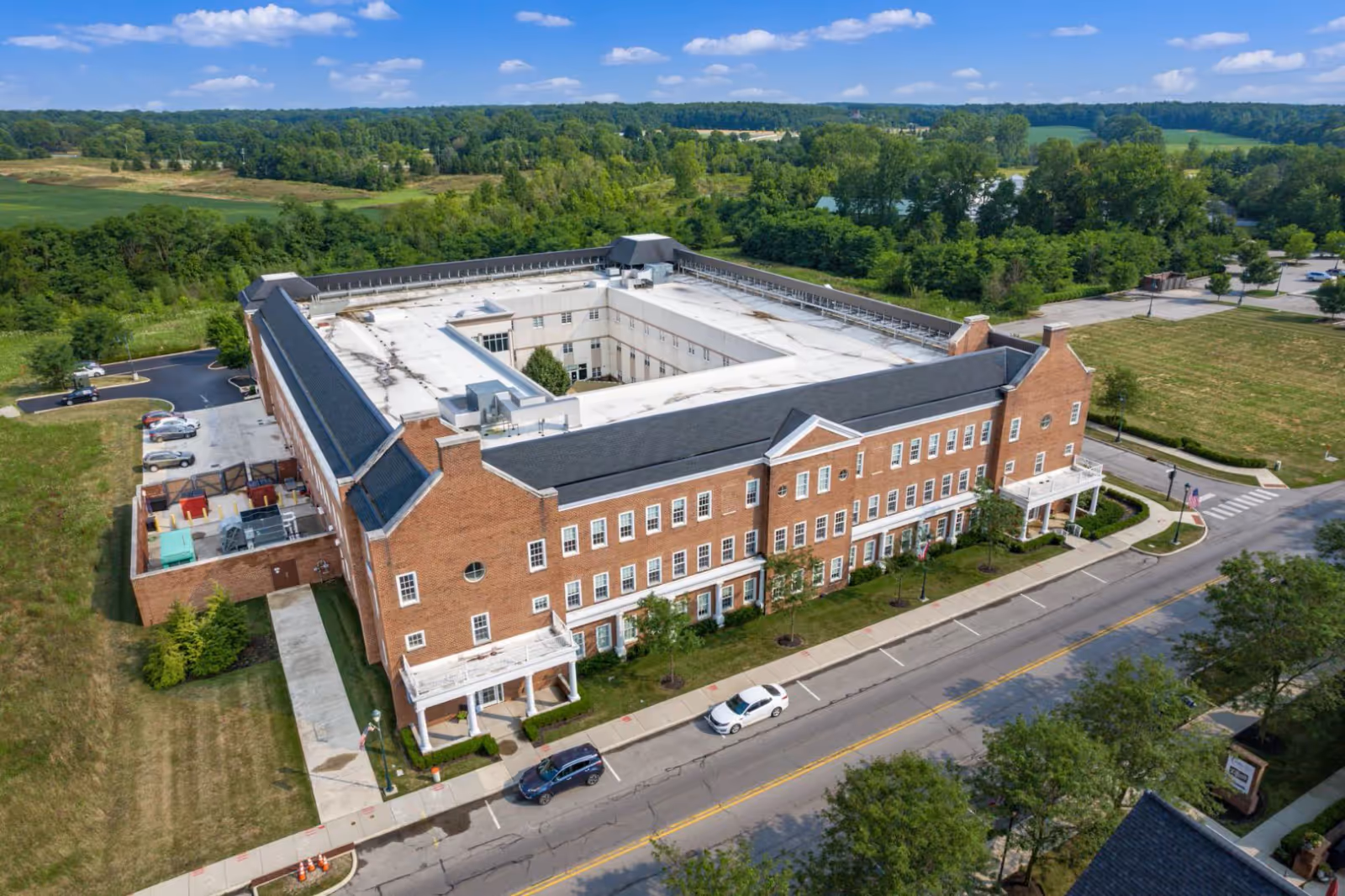 Aerial view of The Avalon of New Albany, a large brick senior living facility, with greenery.