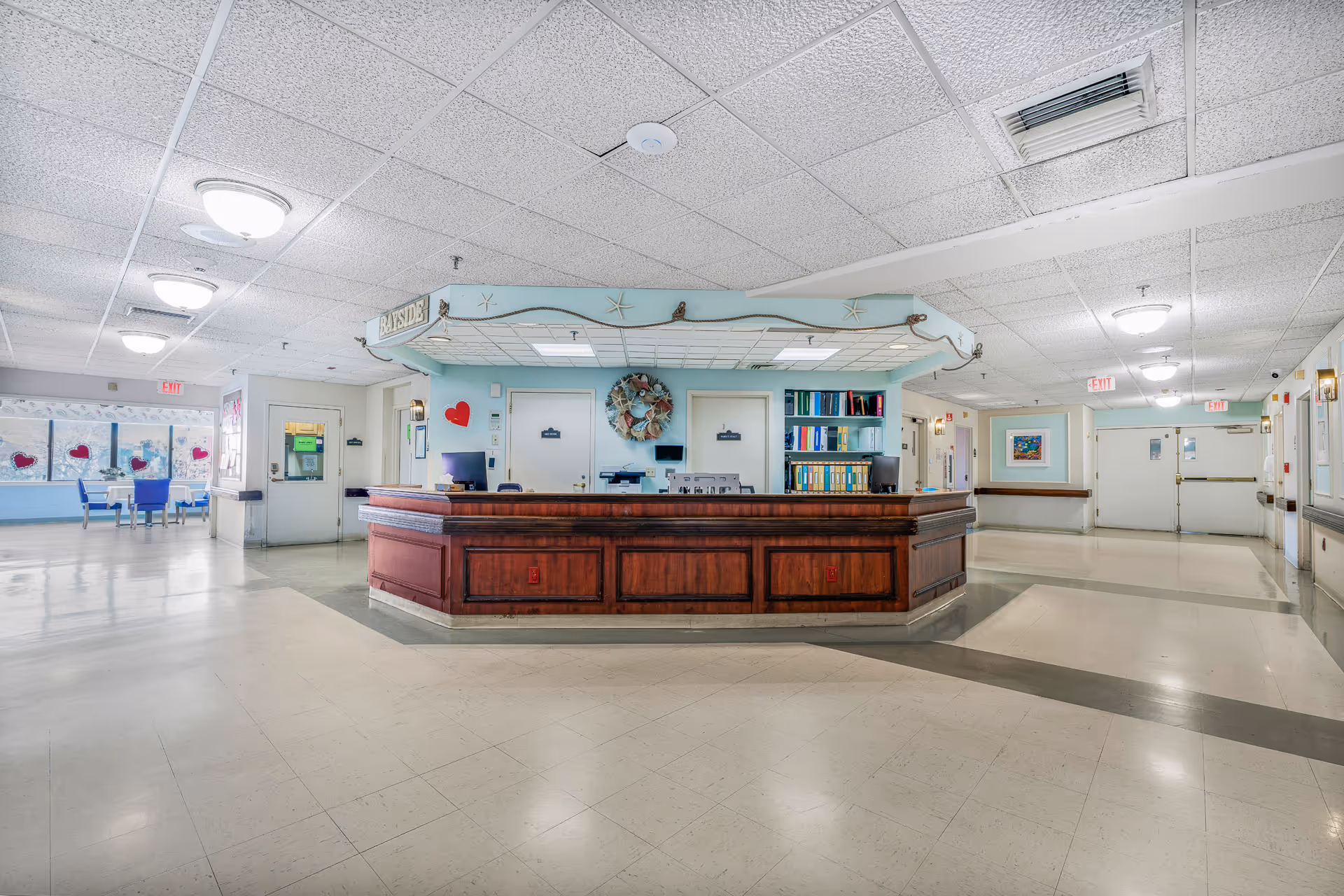 Spacious lobby with a wooden reception desk, blue decor, and seating area.