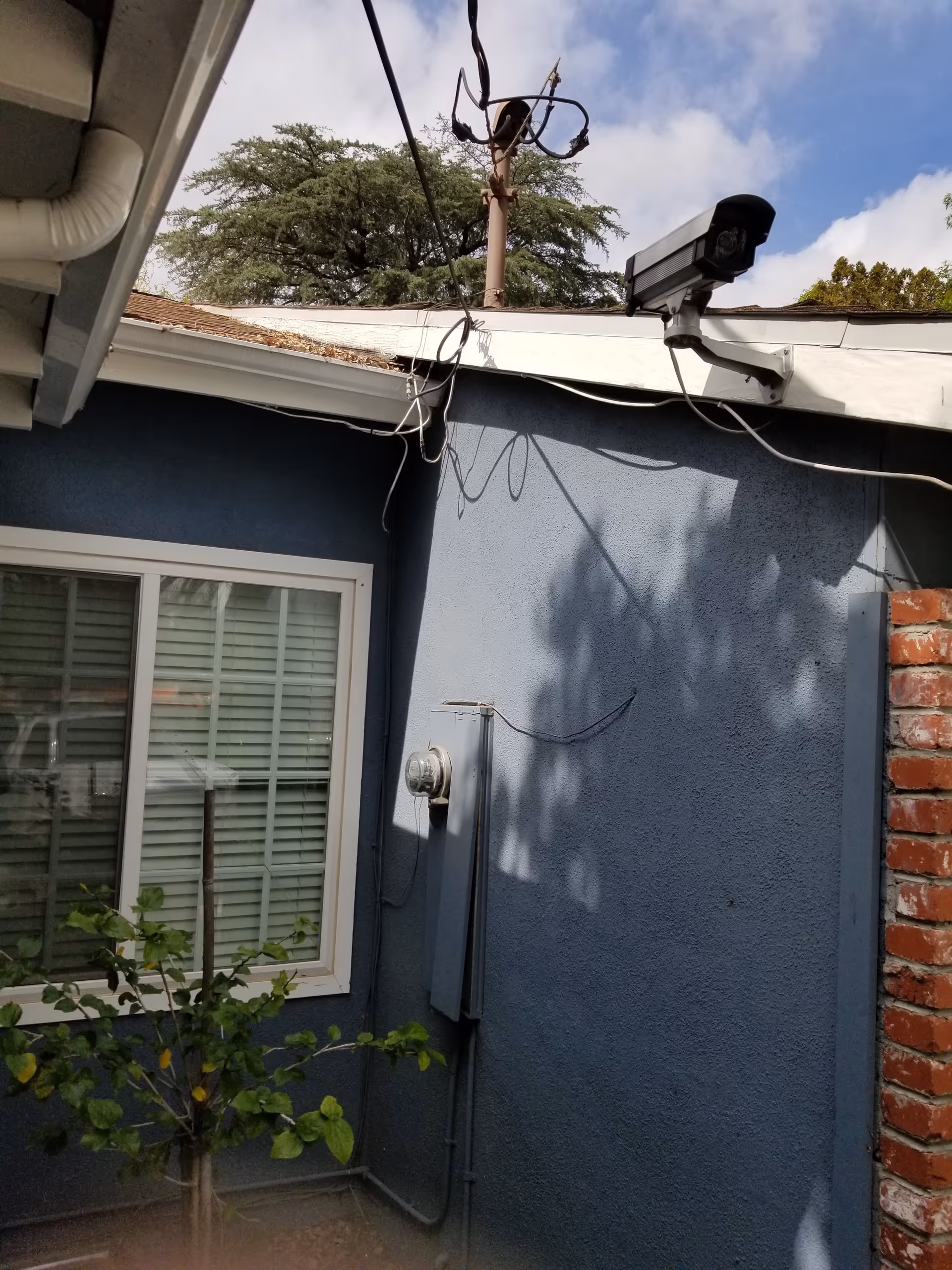 Exterior blue wall of retirement home with window, security camera, and exposed wiring.