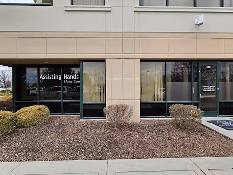 Exterior view of Assisting Hands entrance with glass doors and trimmed shrubs.