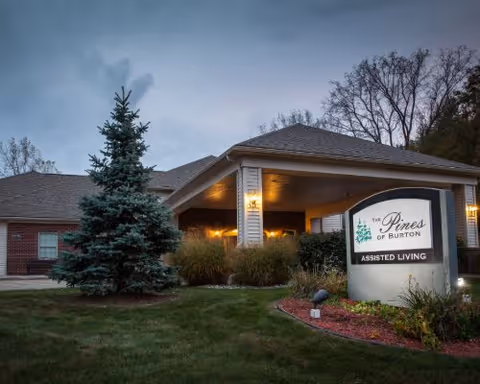 Front exterior view of Pines of Burton Assisted Living with a landscaped entrance sign.
