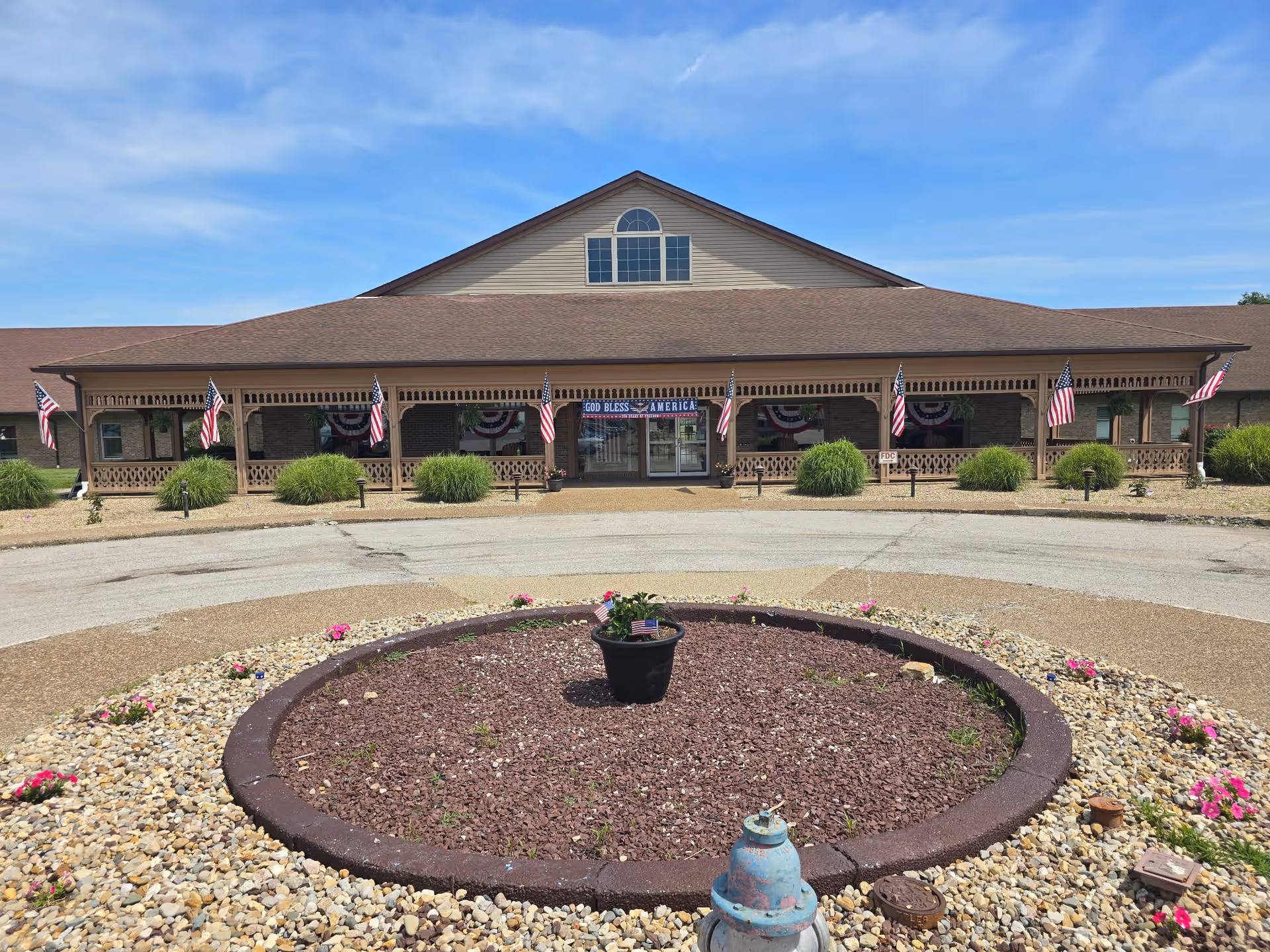 Loogootee Nursing Center exterior with a circular rock garden and patriotic decorations.