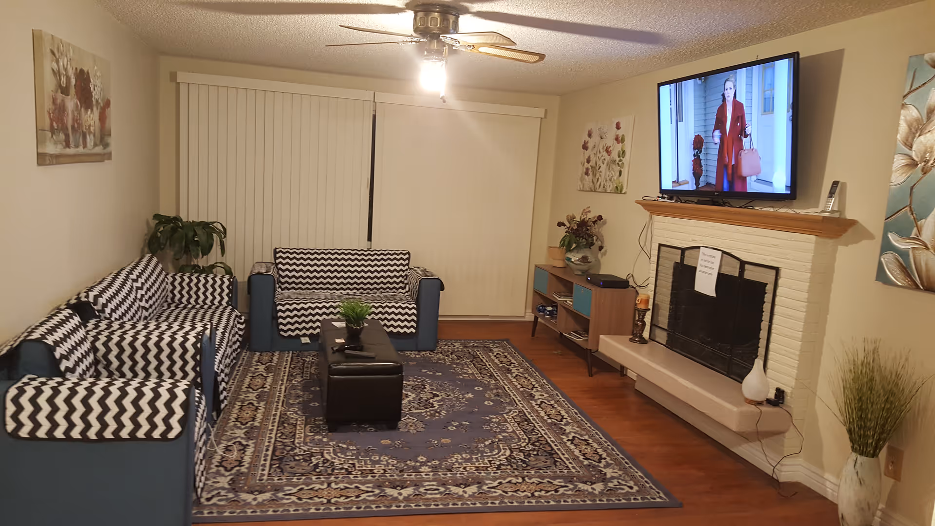 Cozy living room with blue zigzag sofas, rug, coffee table, fireplace, and TV.