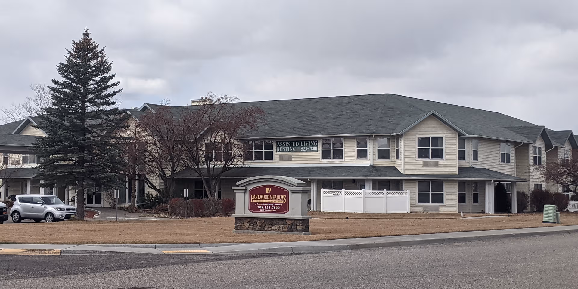 Two-story beige-siding assisted living building with a Parkwood Meadows sign in front.