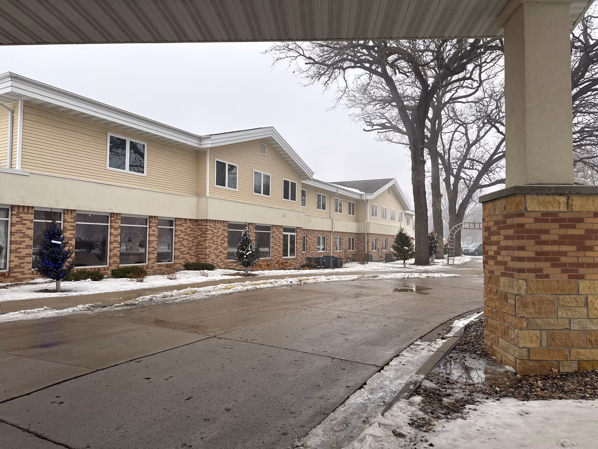Exterior view of Bayside Manor, a two-story brick and beige-siding senior living facility.