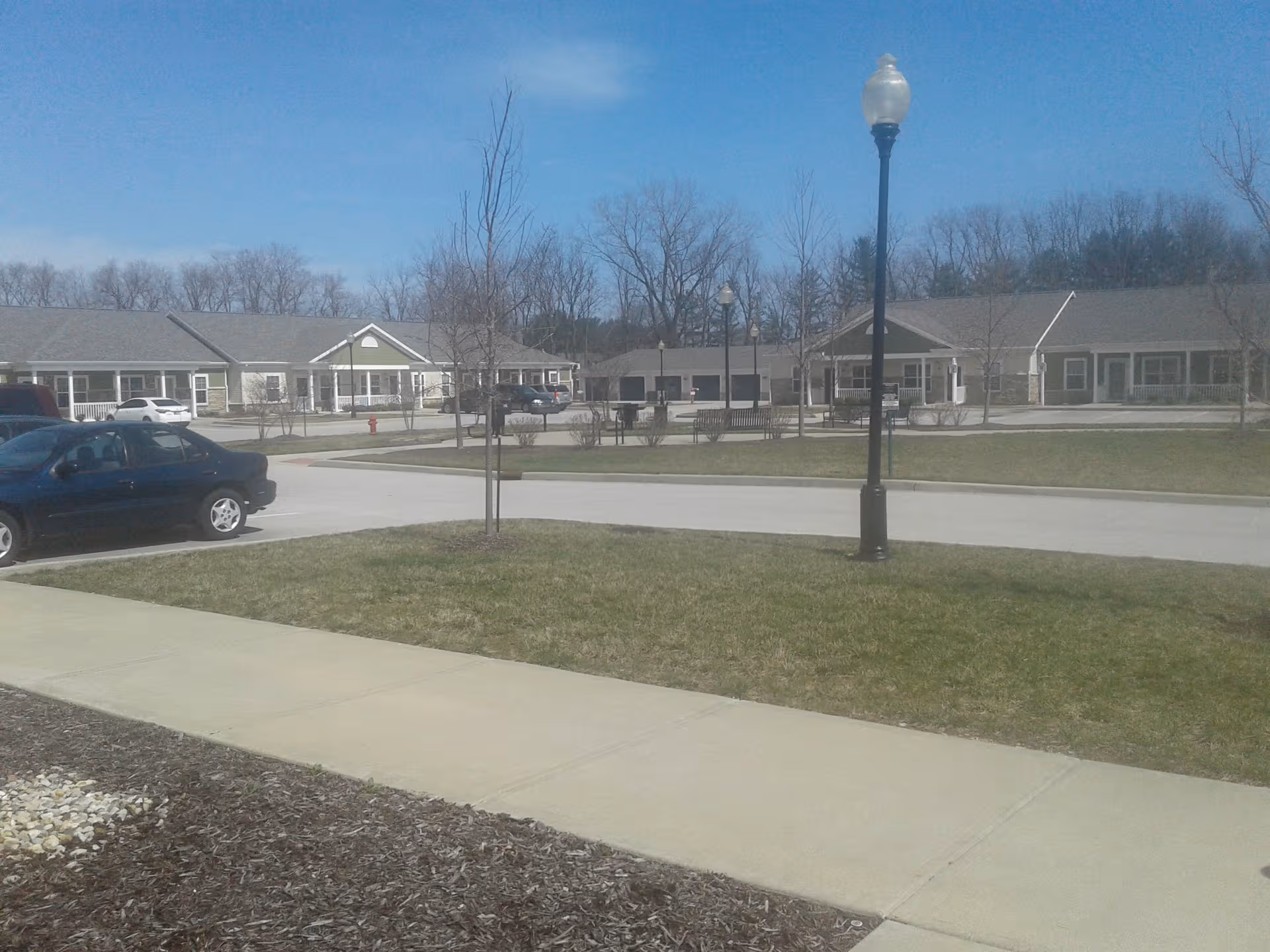 Exterior view of Traditions at Reagan Park with low-rise buildings, parking lot, and lampposts.