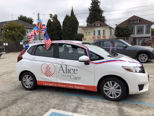 Decorated white Alice Home Care vehicle parked in a lot with flags and banners