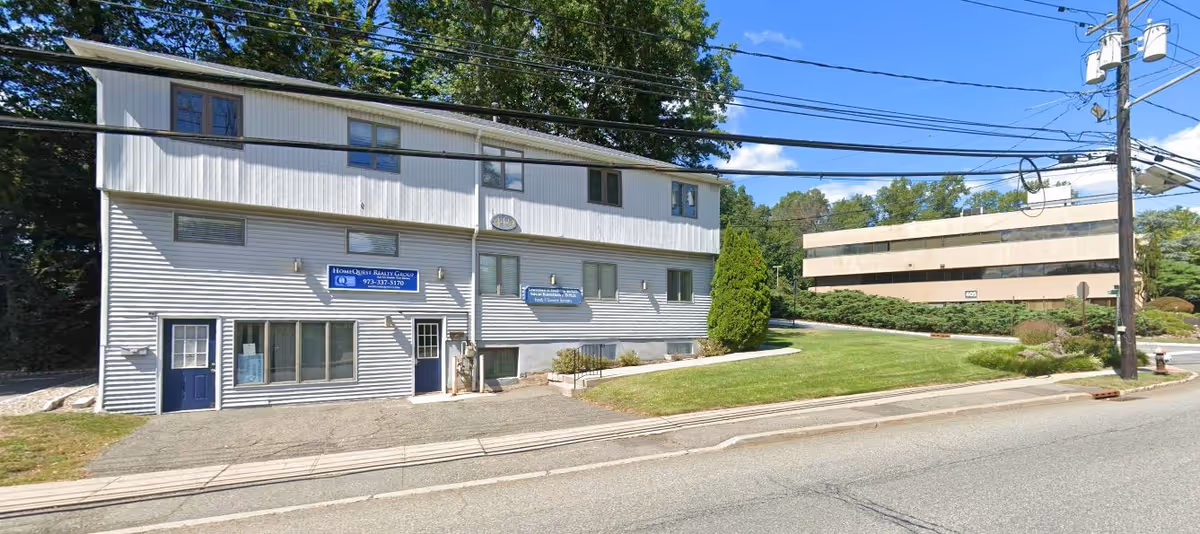 Exterior of Prosperity Home Health Care, LLC: two-story light-gray building with blue doors along a street.
