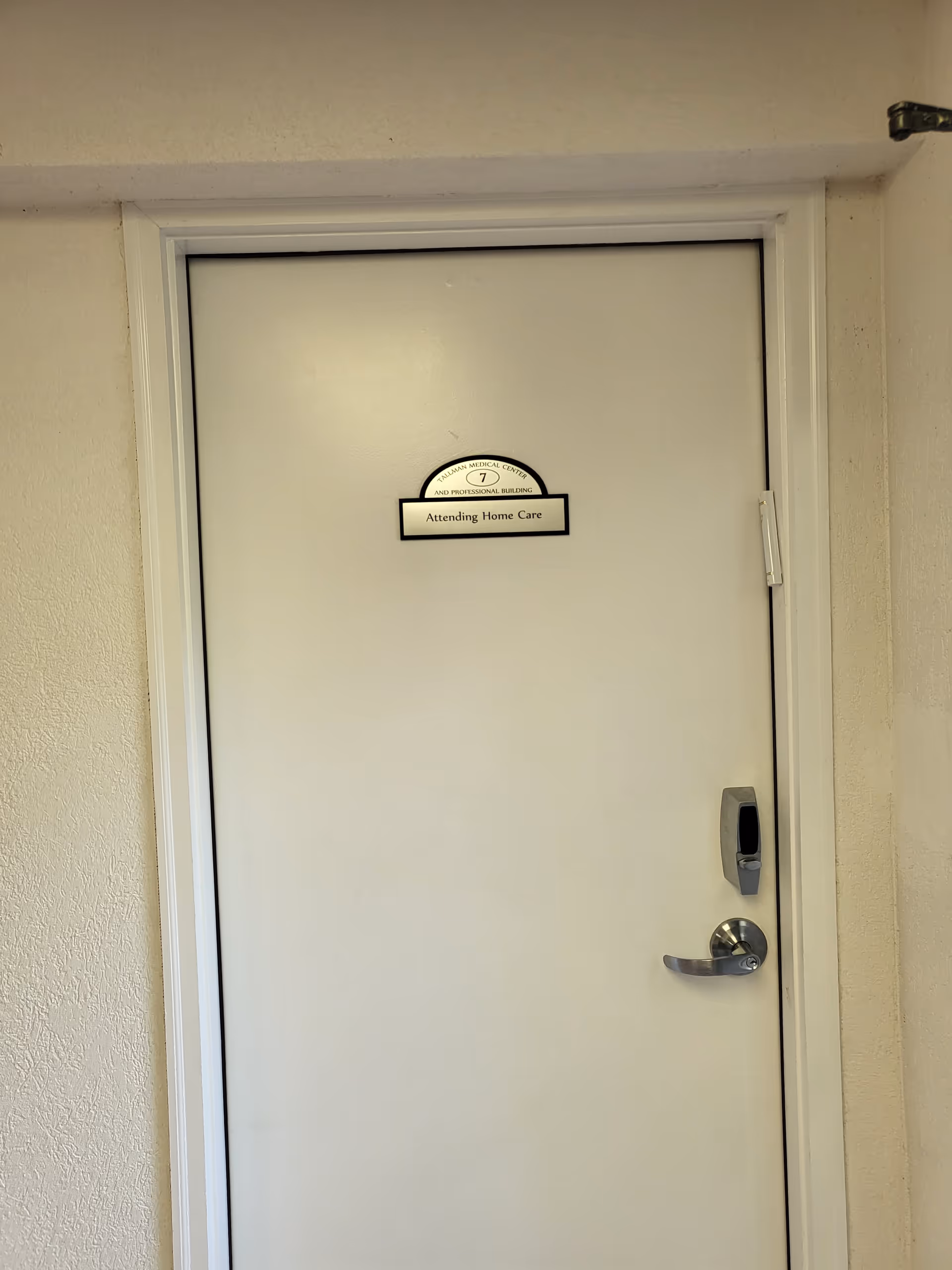 White door with Attending Home Care sign inside a facility hallway.