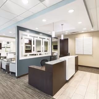 Modern reception desk in a bright lobby with seating and framed mirrors.