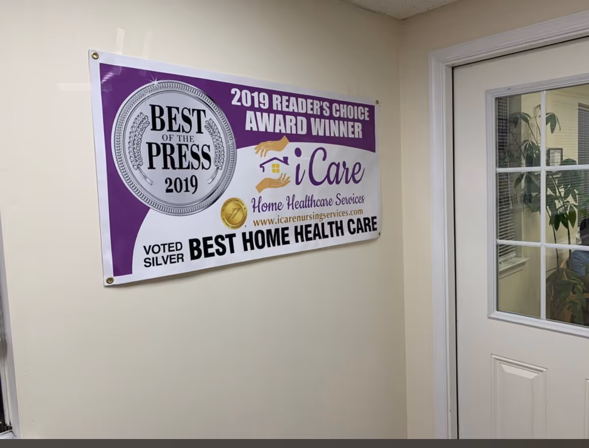 A purple award poster for iCare Home Healthcare Services hangs on hallway wall near a door.