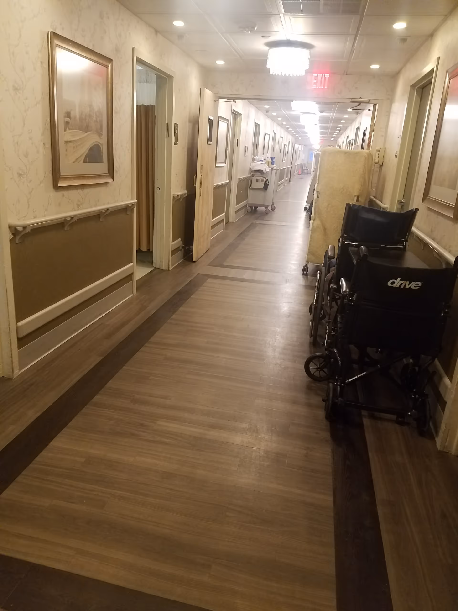 Long interior hallway of a senior living facility with a wheelchair near the wall.