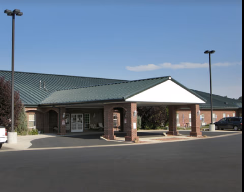 Exterior view of Absaroka Senior Living entrance with brick columns and green roof.