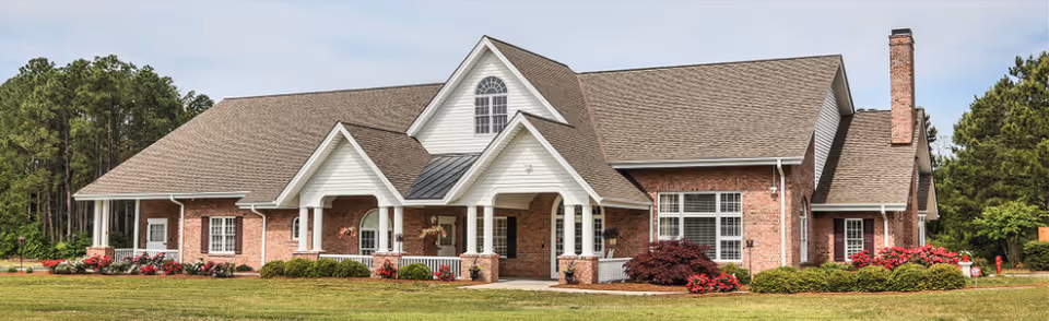 Front view of a brick senior living facility with landscaped grounds.