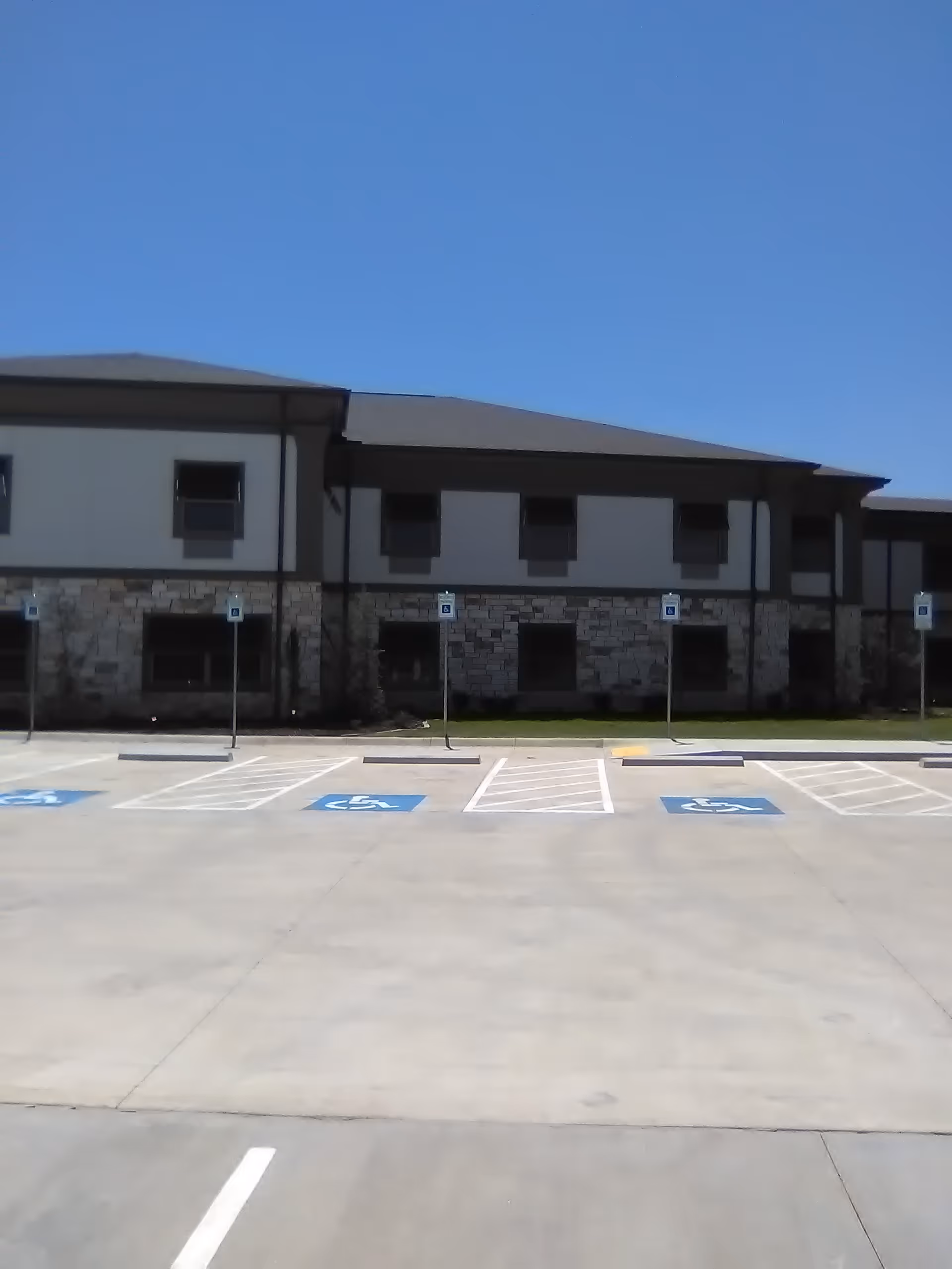 Exterior view of a senior living facility with a stone facade and handicapped parking.