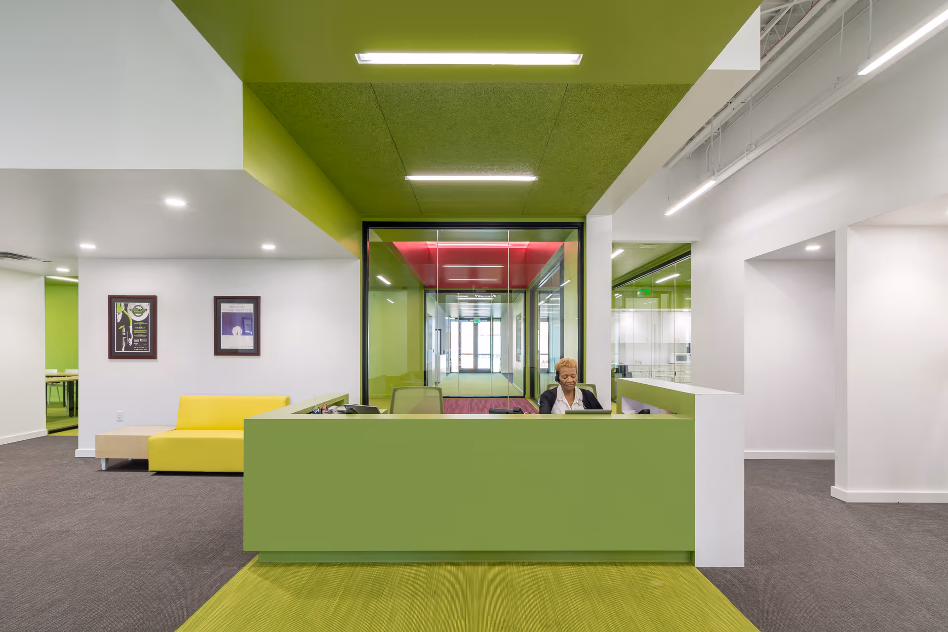 Bright modern reception area with lime-green accents and a receptionist at the desk.