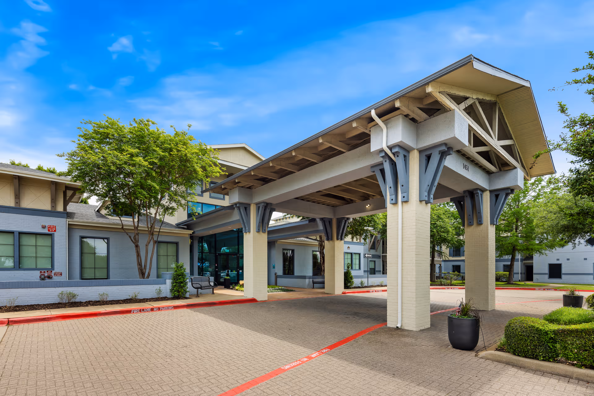 Front entrance of a senior living facility with porte-cochere and driveway.