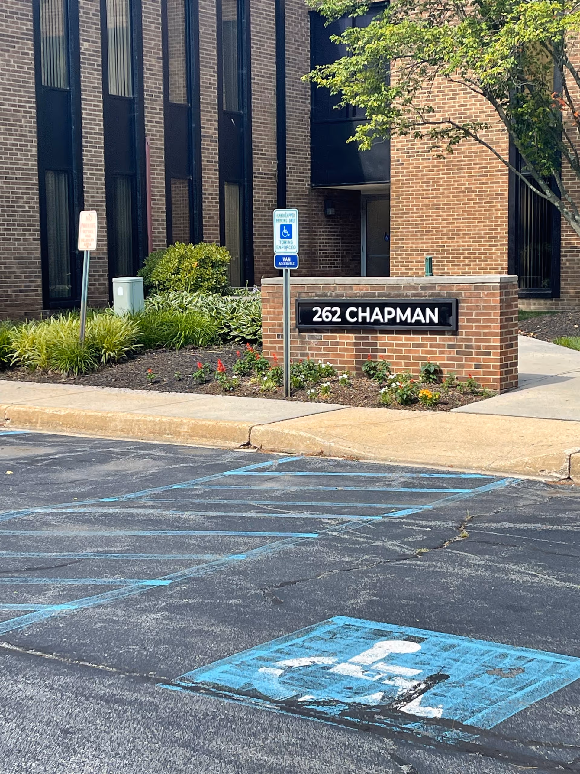 Exterior view of a brick building with a 262 Chapman sign and handicapped parking.
