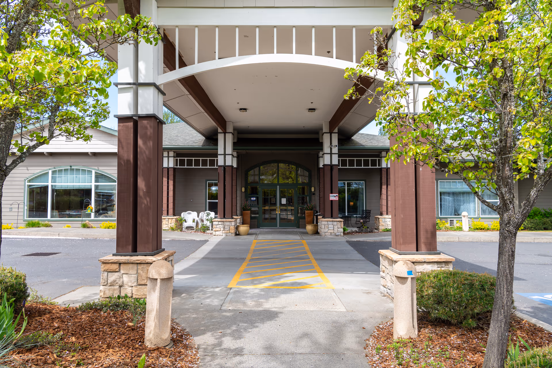 A covered entrance with tall pillars opens to the Providence Brookside Manor building.