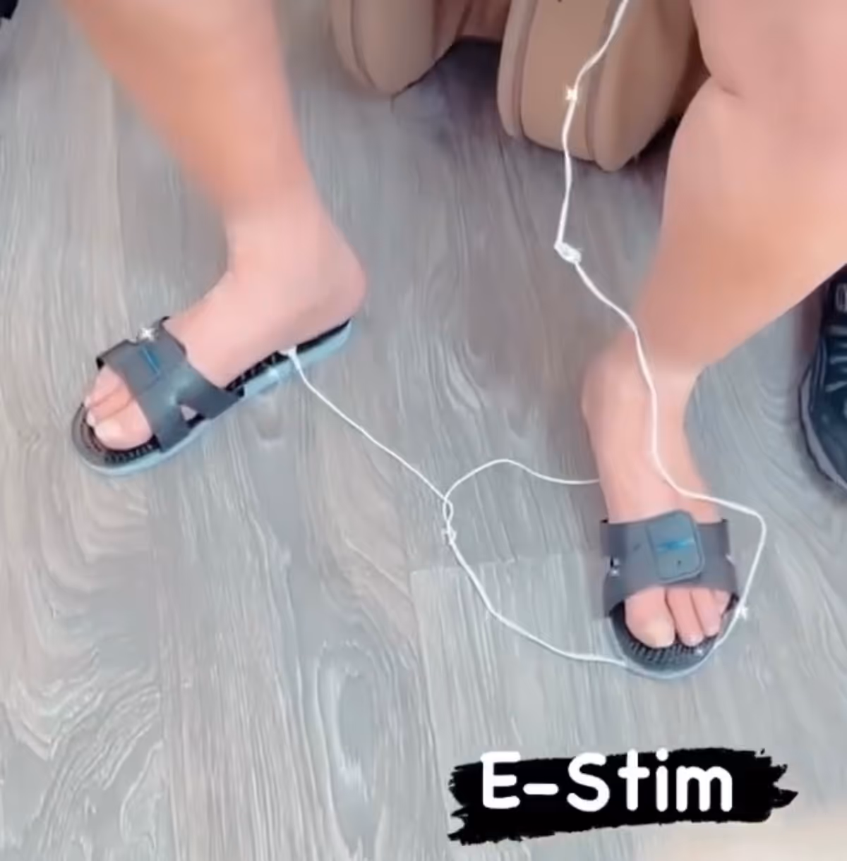 Close-up of a resident's feet in sandals on a wooden floor with E-Stim wires.