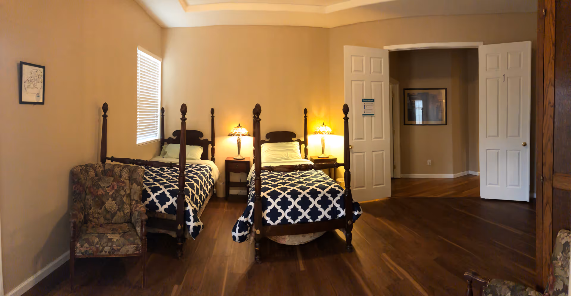Two twin beds with dark wood frames and lamps flank a small nightstand in a bedroom.