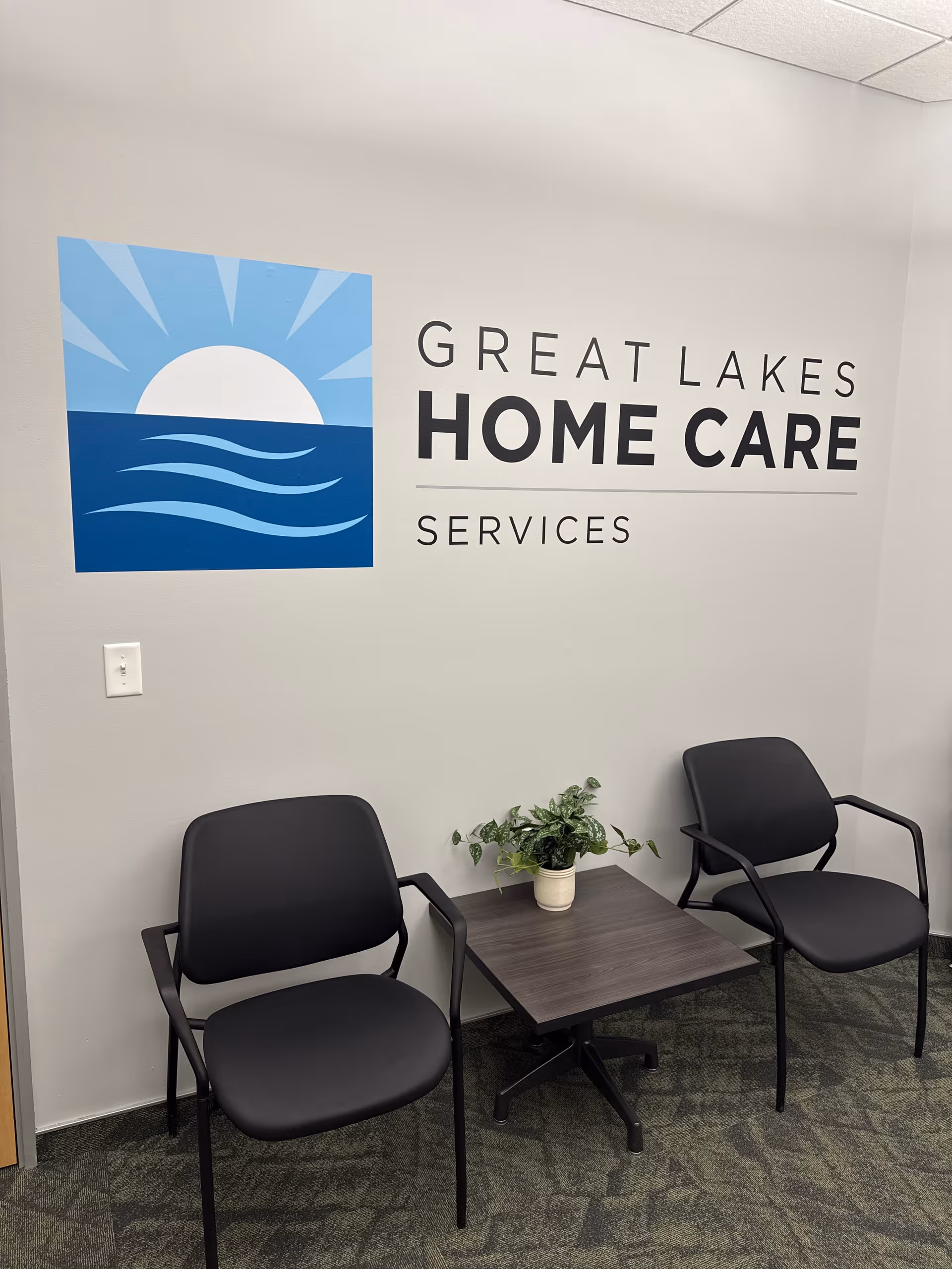 Lobby area with Great Lakes Home Care Services logo, two chairs, a table, and a plant.