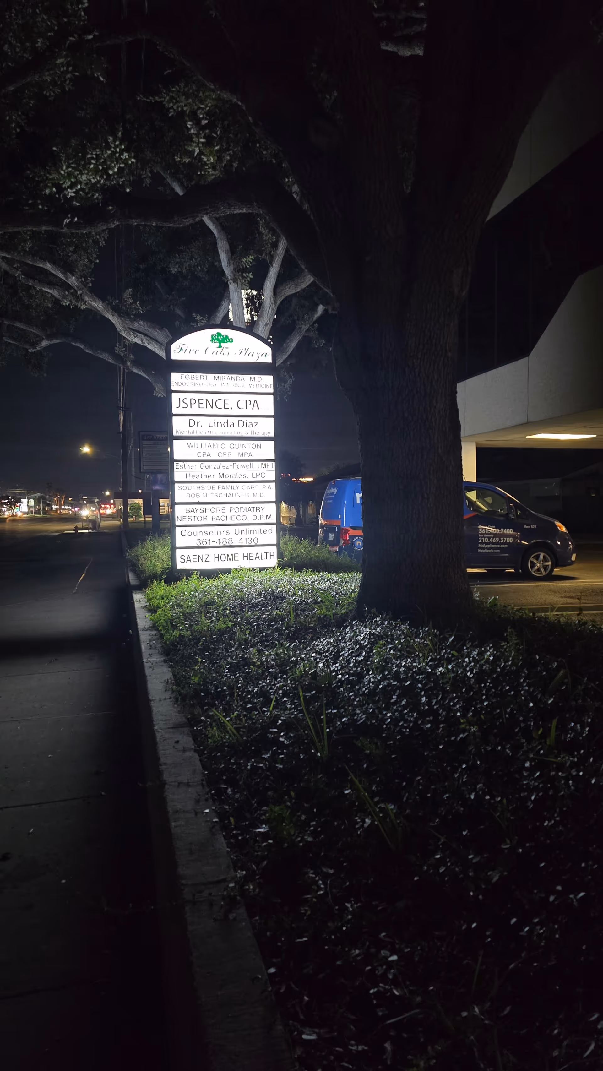 A nighttime exterior scene shows a tall sign for Saenz Home Health beside a tree.