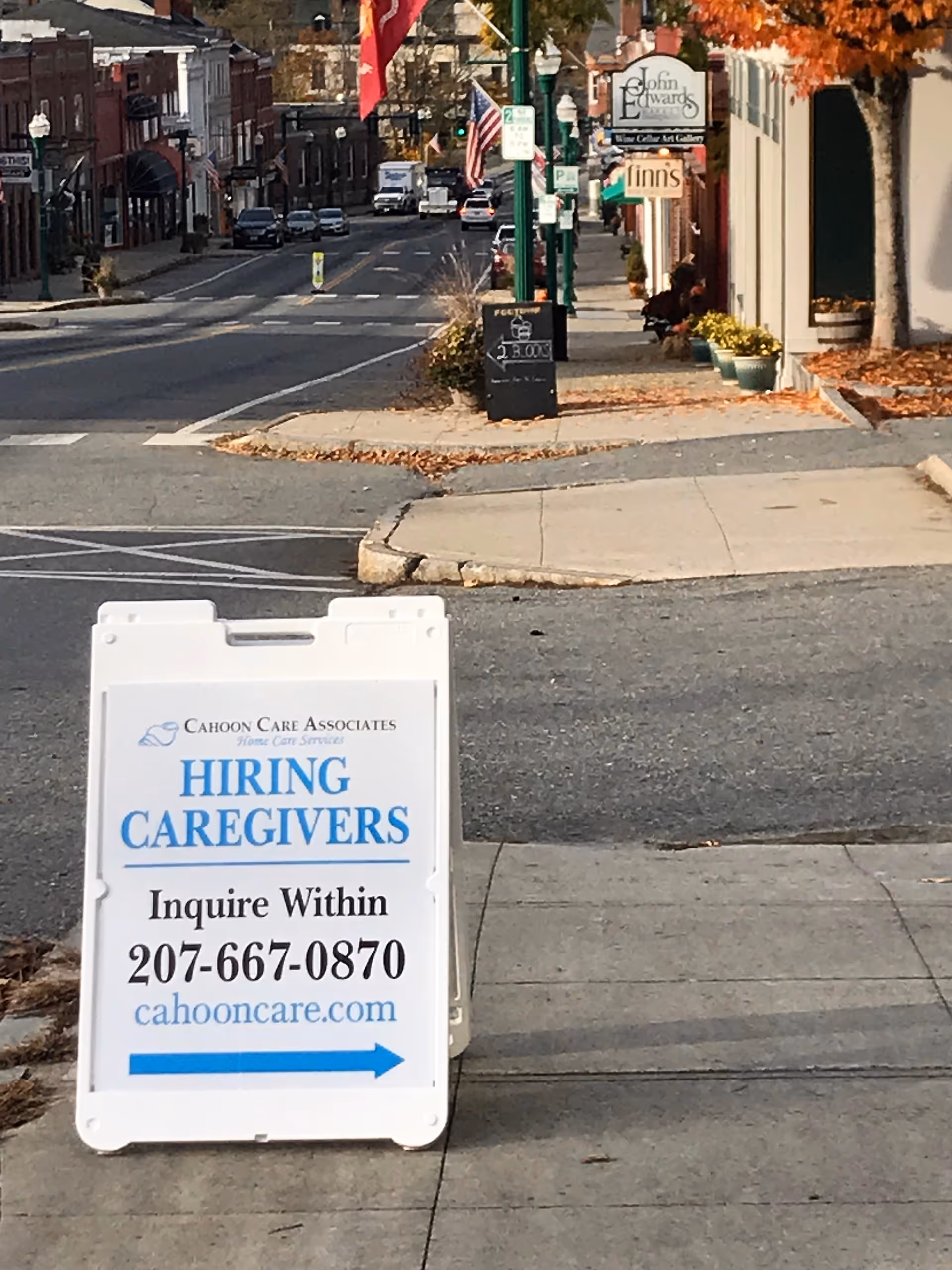 Outdoor street view showing a Cahoon Care Associates hiring caregivers sign on the sidewalk.
