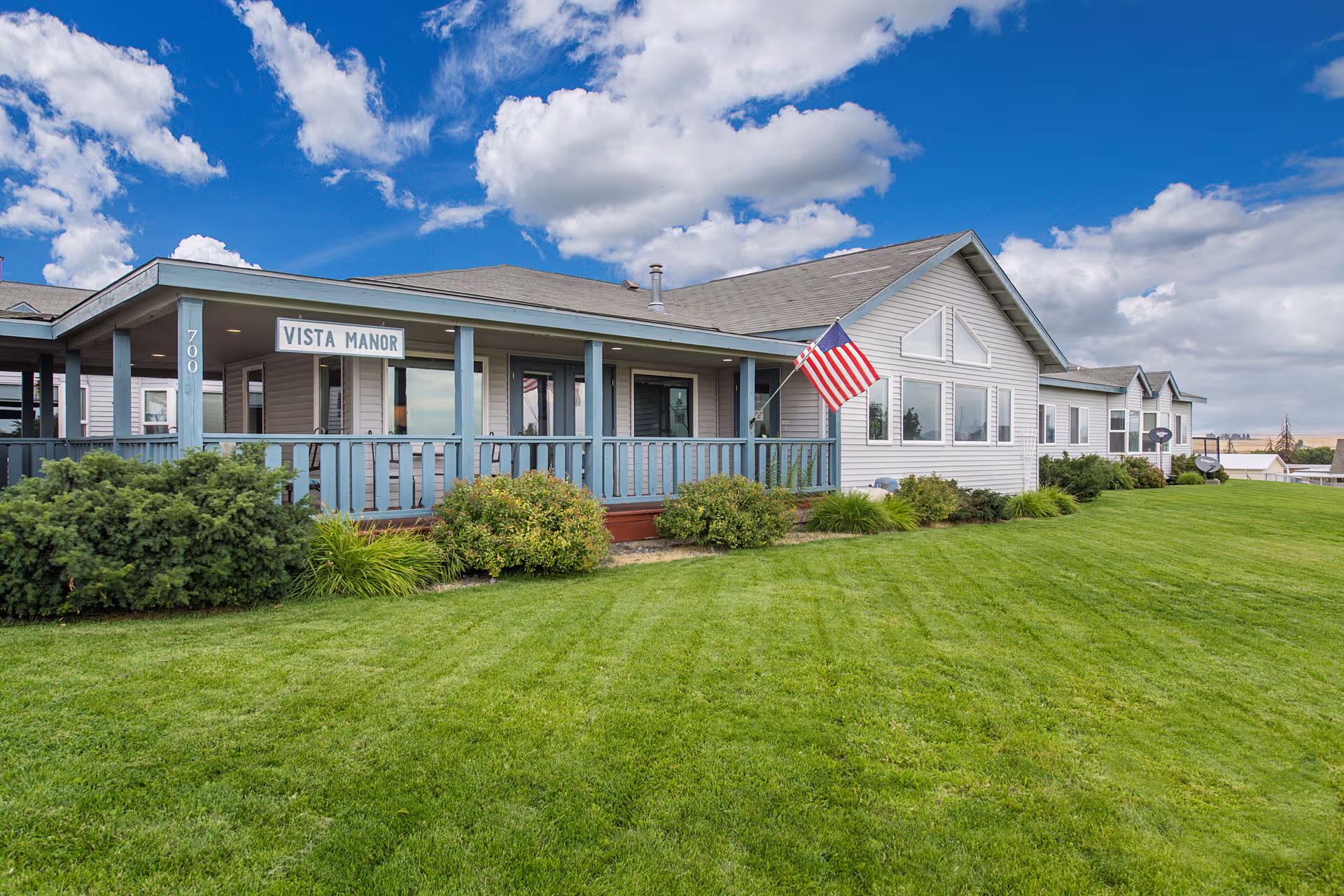 Single-story Vista Manor building with a porch, flag, and well-kept lawn.