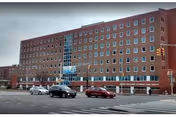 Front facade of a large brick senior care facility with many windows and cars.