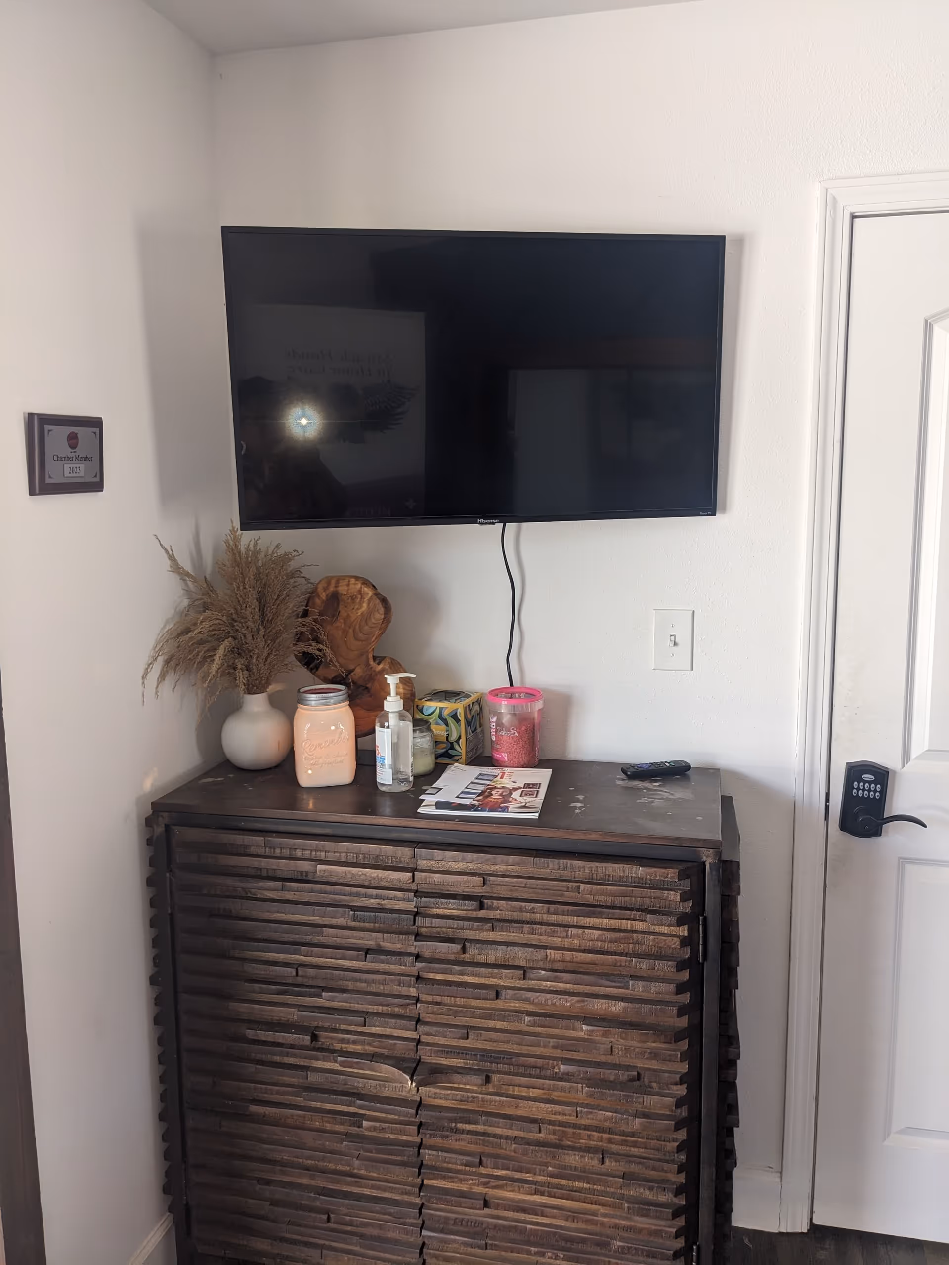TV mounted on wall above a dark cabinet with decor and a door
