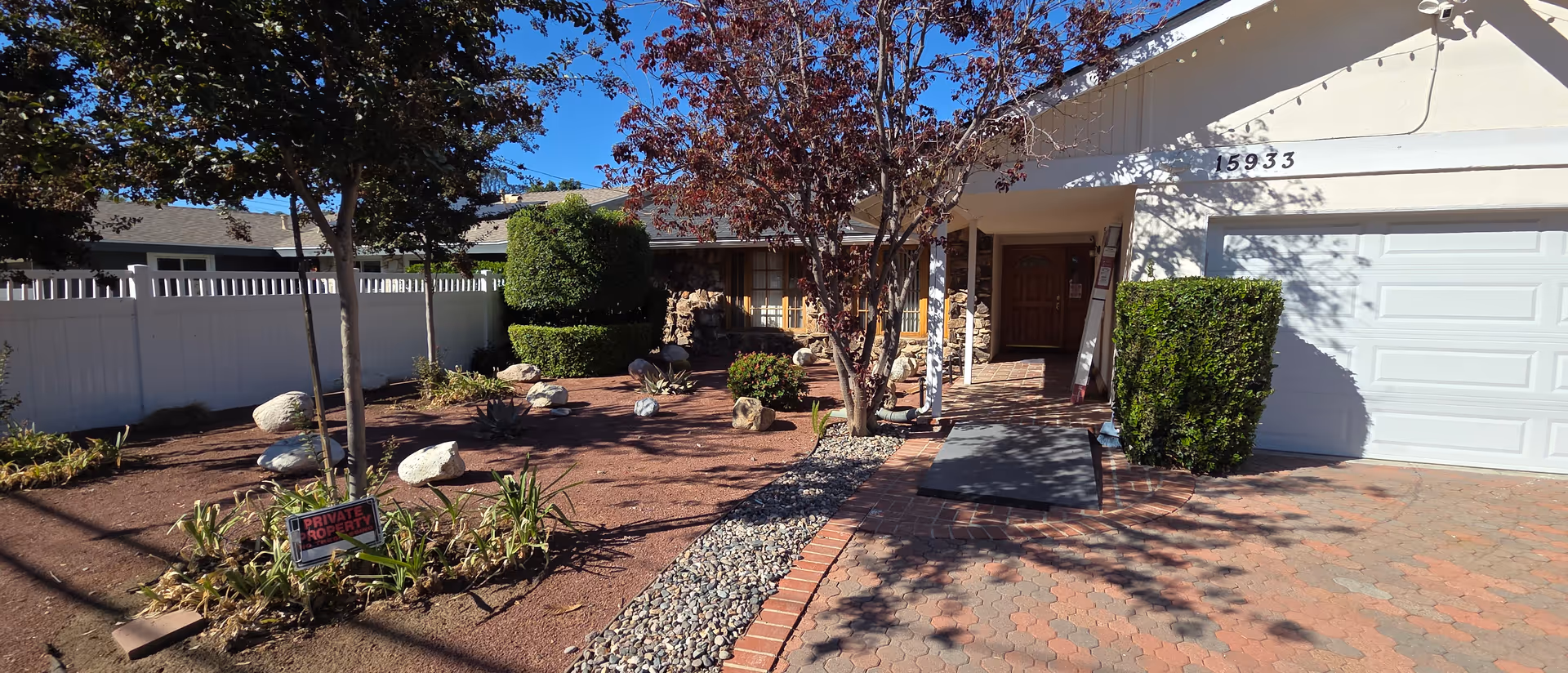 Senior living facility exterior with brick driveway, landscaped yard, and entry toward a two-car garage