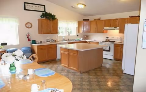 Bright kitchen in a senior living facility with an island, cabinets, and dining table.