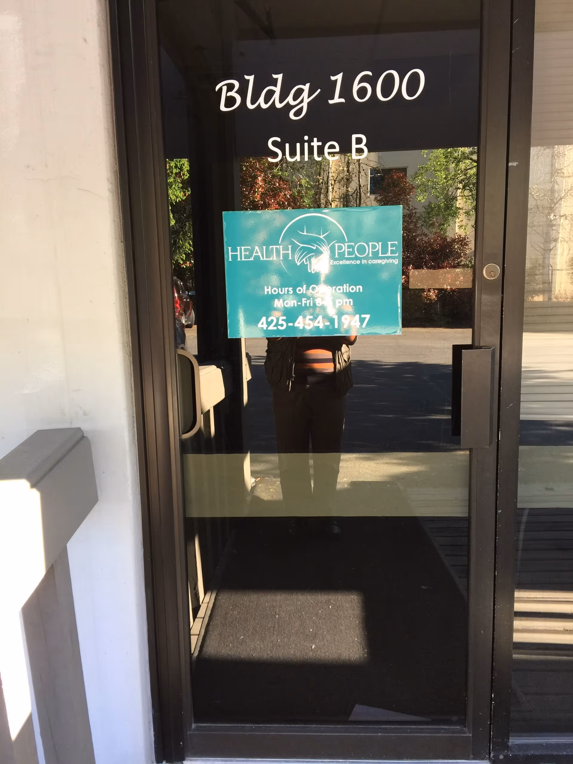 Glass entrance door displaying Building 1600, Suite B, with a Health People banner.