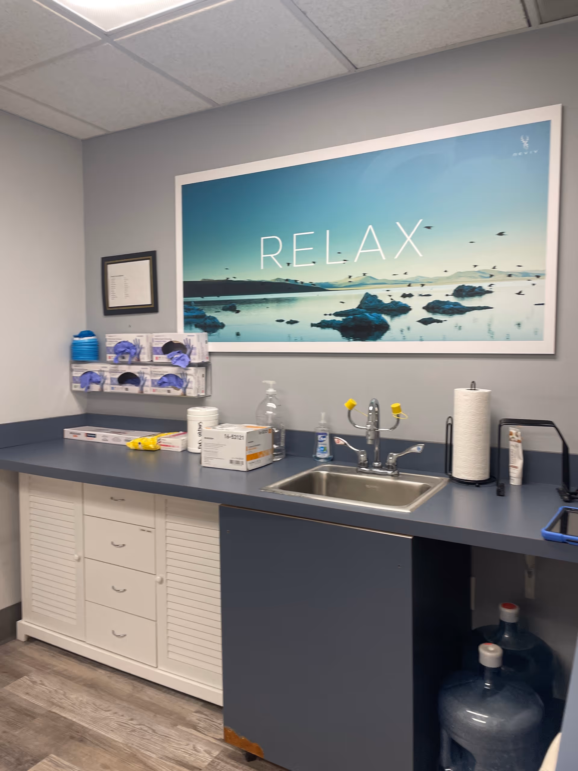 Medical prep counter with sink, supplies, and a RELAX poster on the wall.