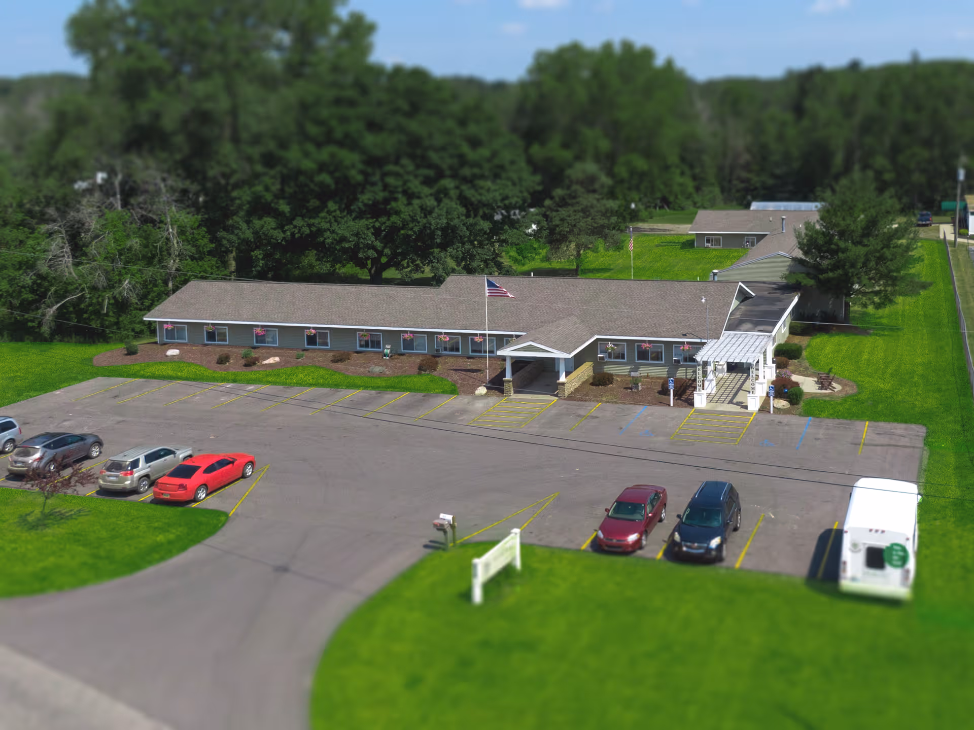 Single-story senior living facility with front entrance, flagpole, and a parking lot.