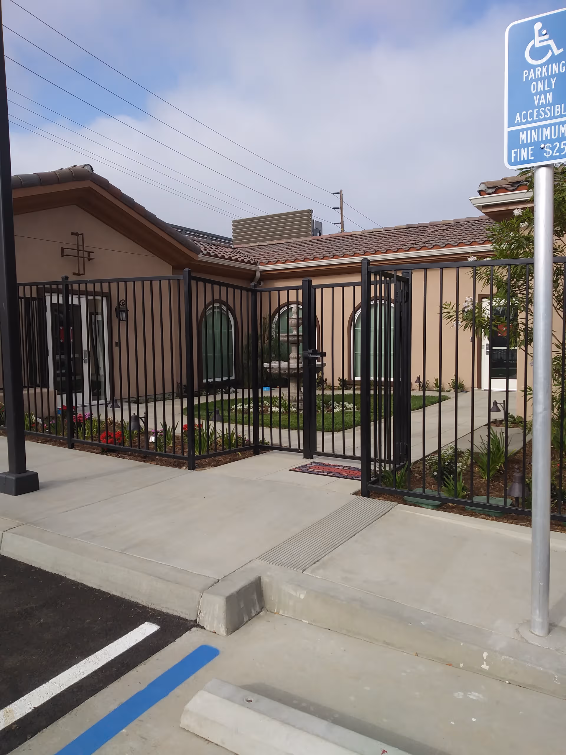 Exterior view of a gated entrance to a memory care facility with arched windows.