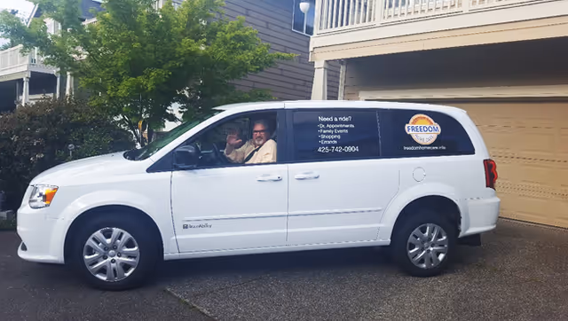 White Freedom Home Care van parked outside a residential building, with a driver visible.