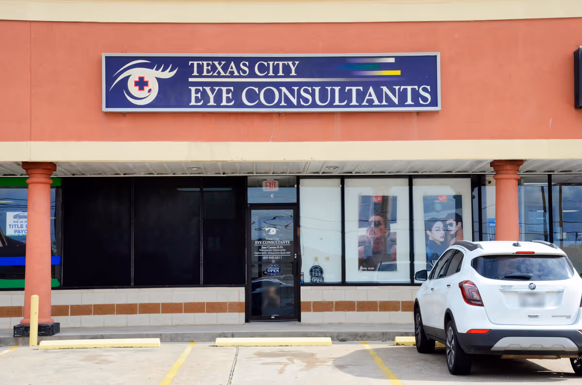 Front view of a storefront with Texas City Eye Consultants sign and a white SUV parked.