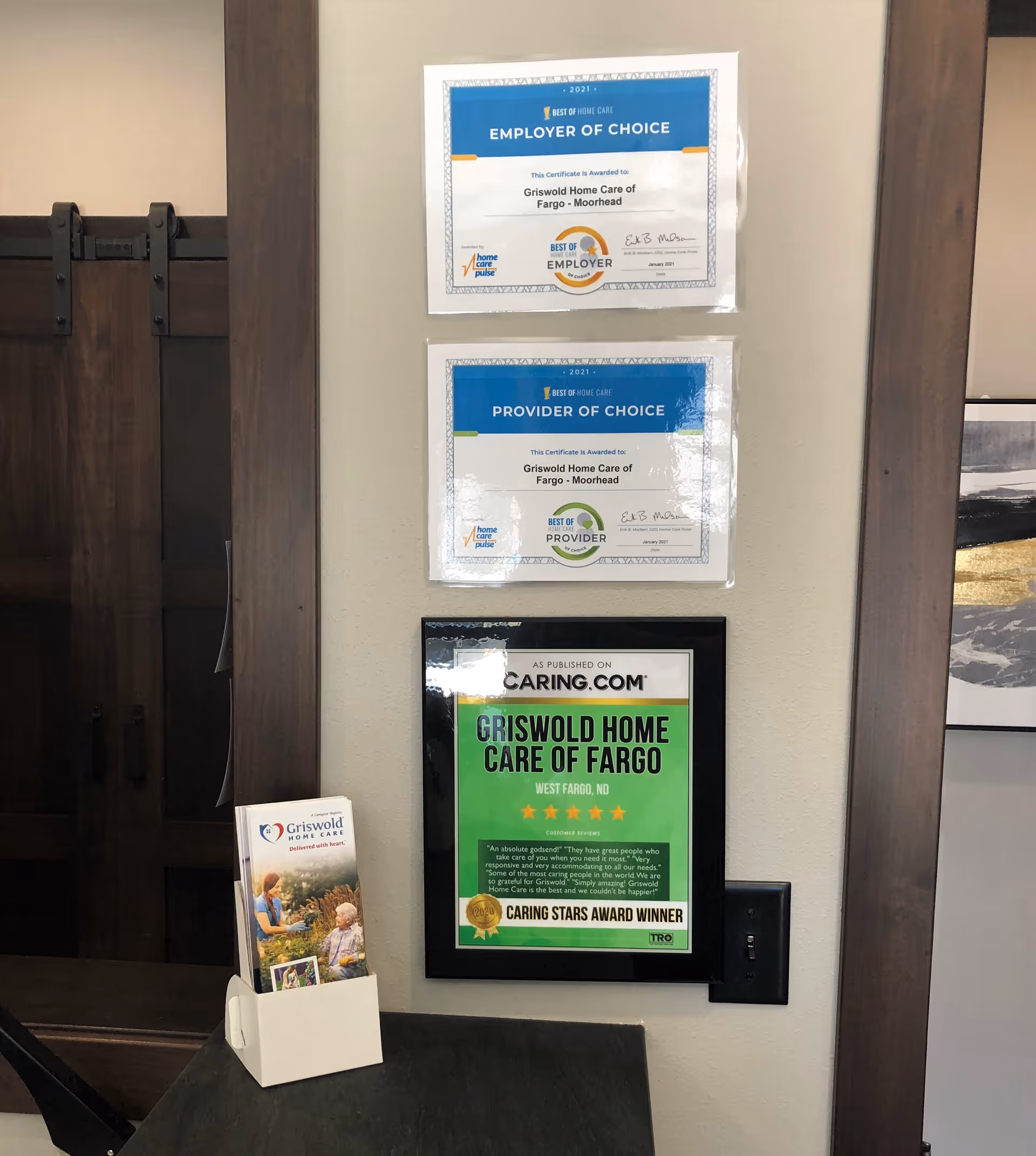 Interior wall displays awards and a brochure rack in a senior care facility.
