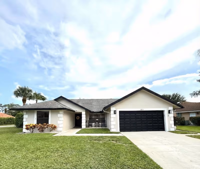 Single-story building with a double garage, front lawn, and entrance porch.