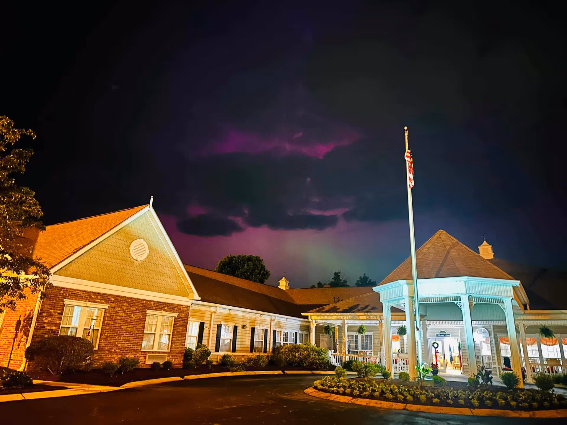 Night exterior of Morning Pointe of Frankfort with illuminated entrance and flagpole.