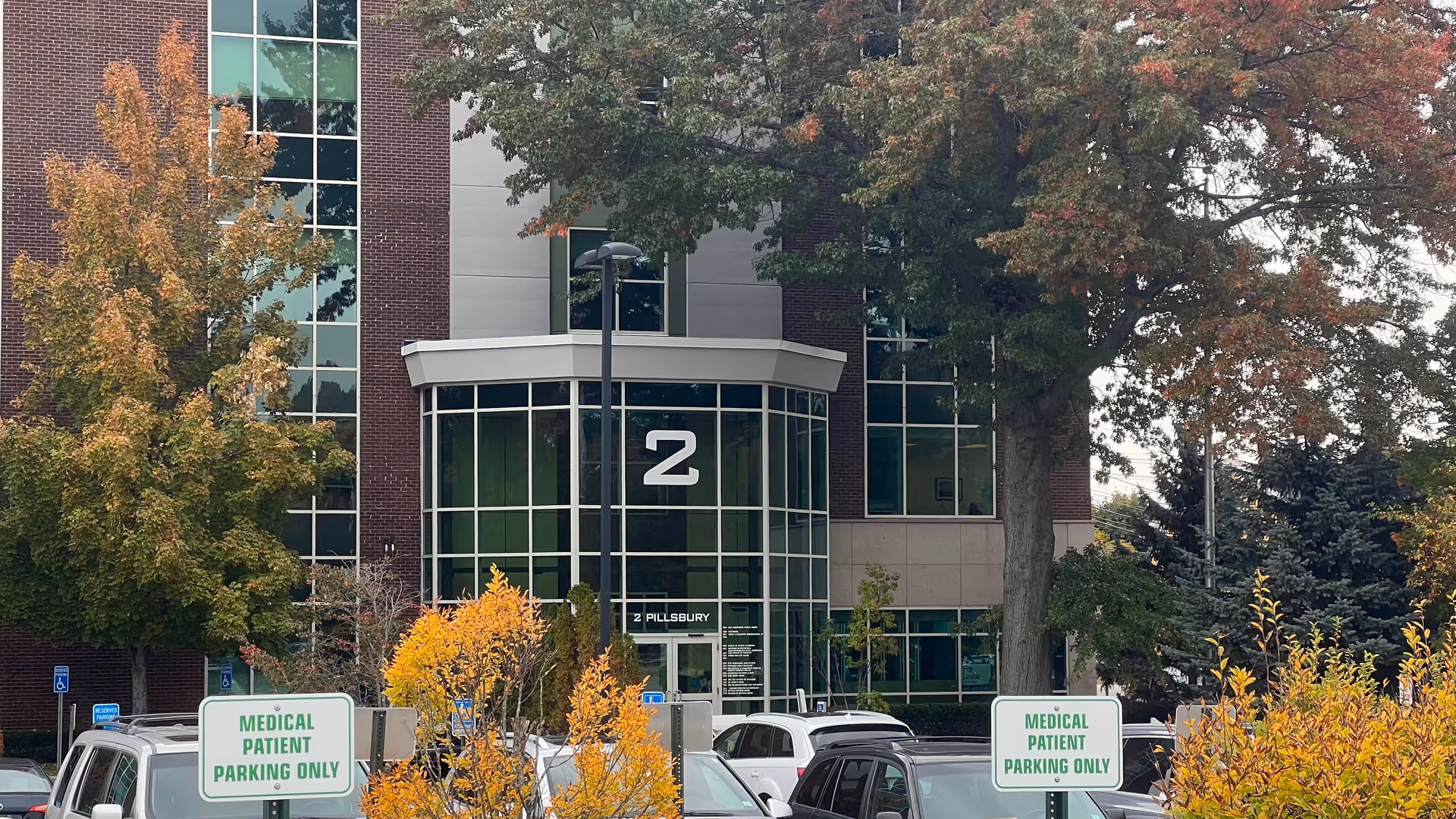 Exterior view of brick and glass building entrance with a large number 2 and parking.
