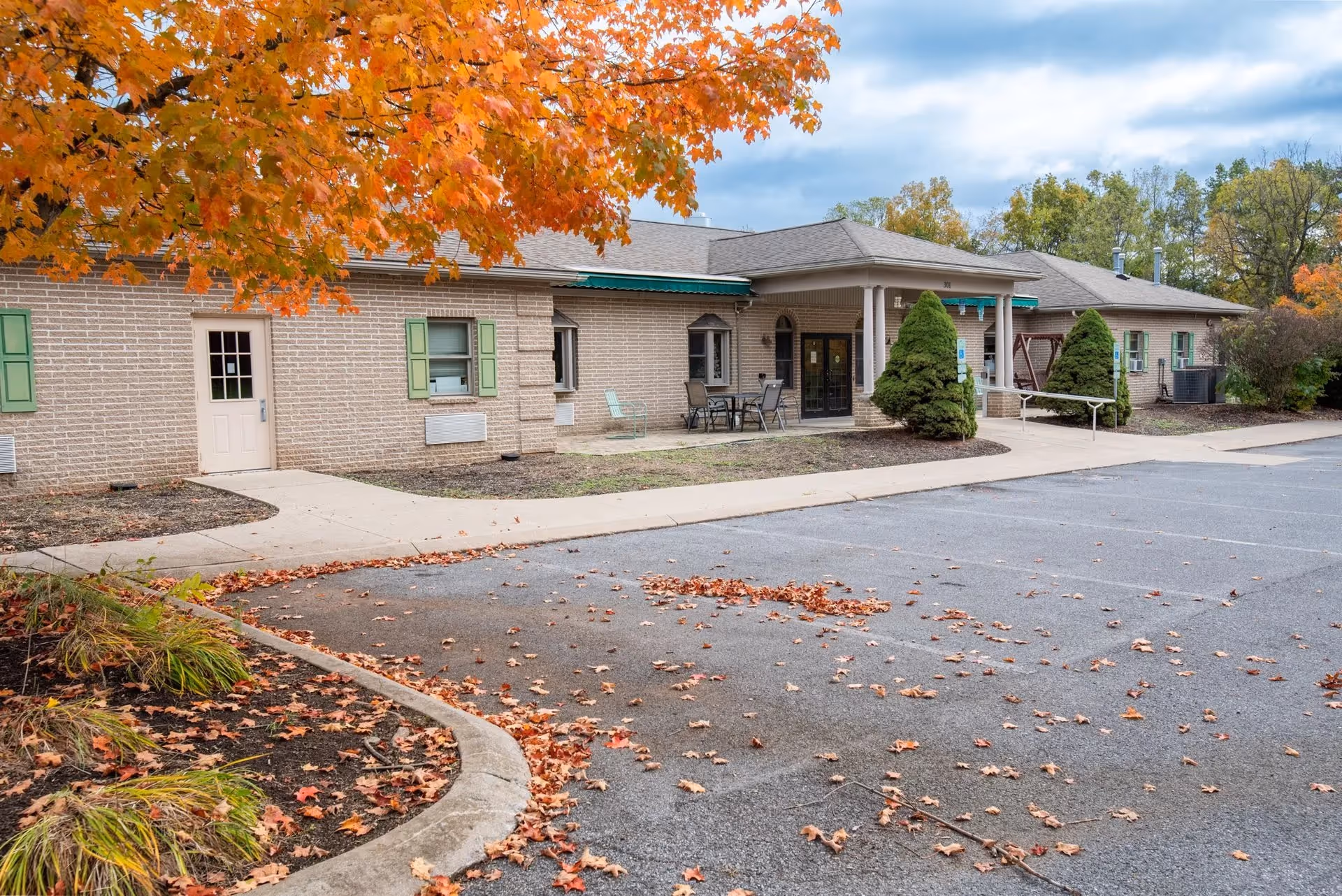 Exterior view of Wynwood House Personal Care Homes with a brick facade, entrance, and autumn trees.
