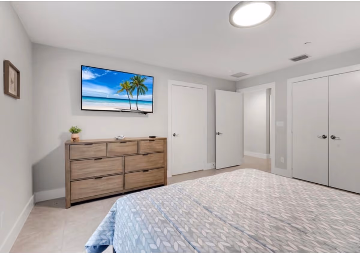 A tidy bedroom in a senior living facility with a dresser, TV, and bed.
