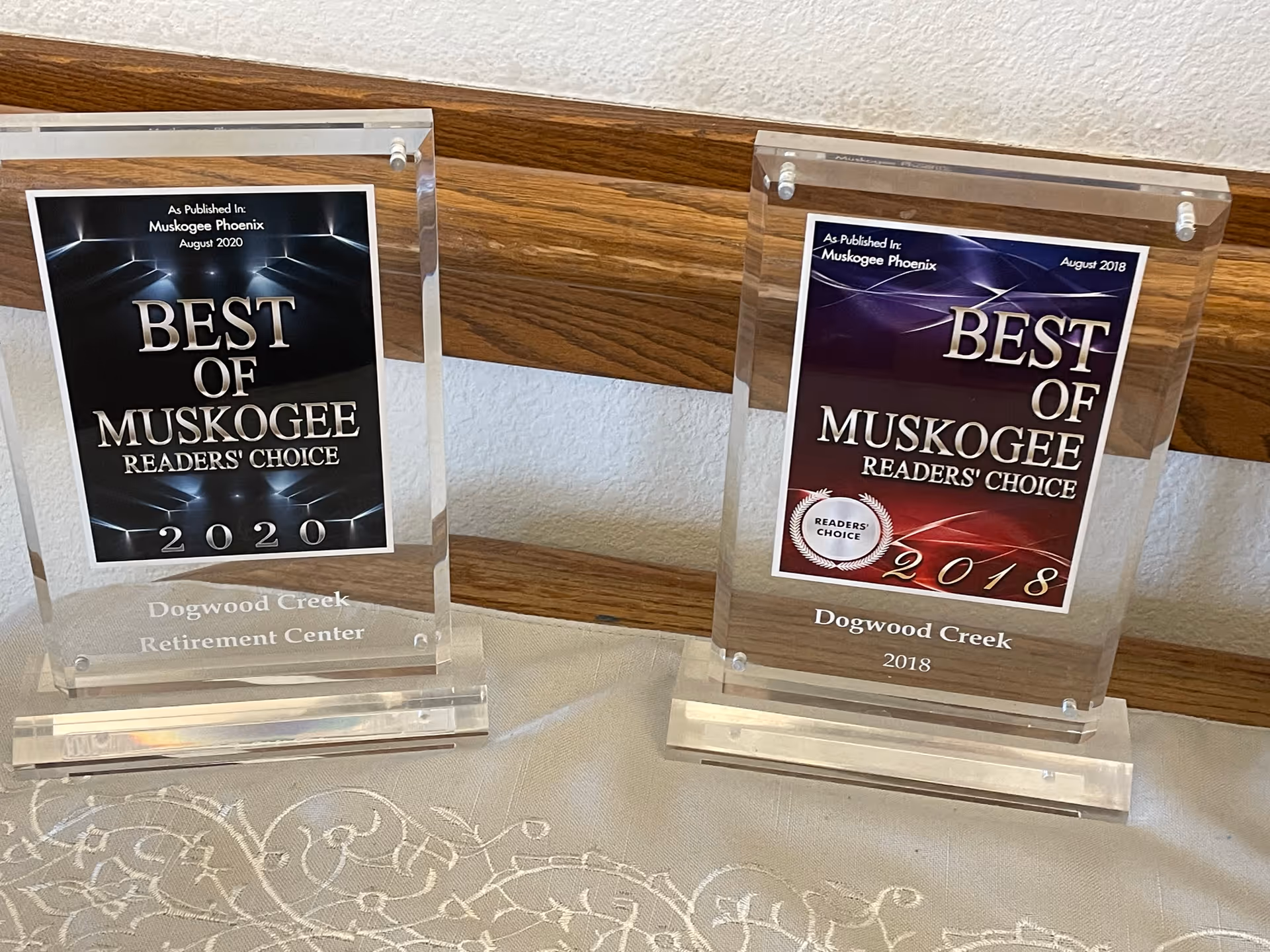 Two "Best of Muskogee" reader's choice award plaques for Dogwood Creek displayed on a table against a wood-paneled wall.